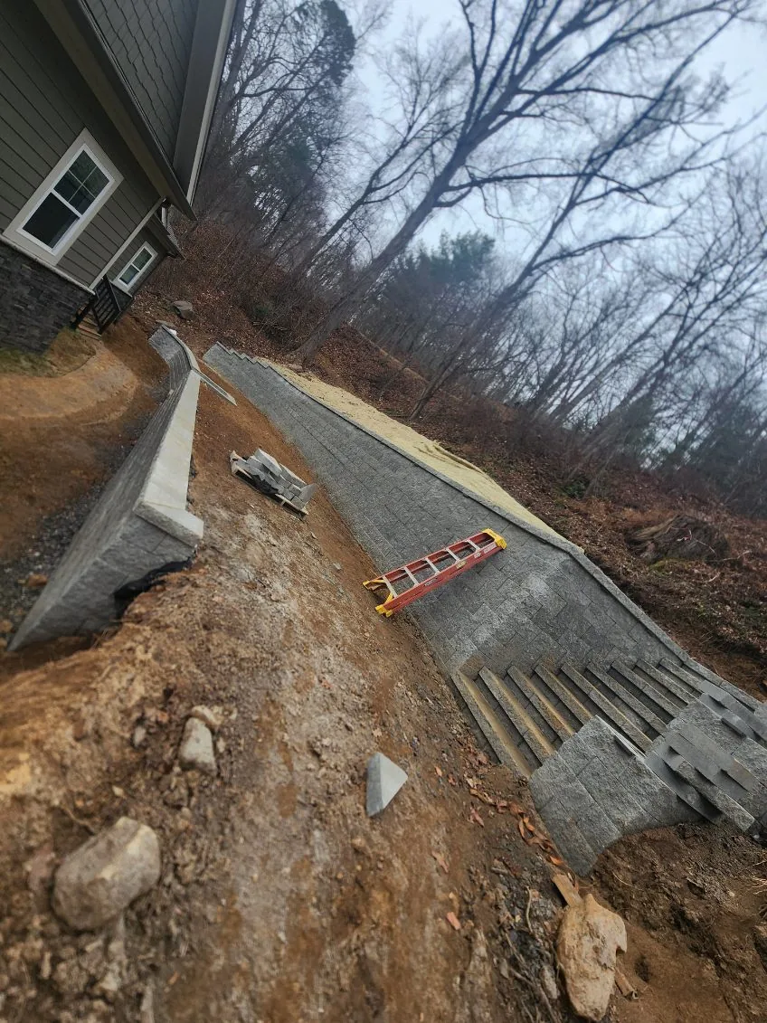 Segmental block retaining wall with a built-in stair beside a new home
