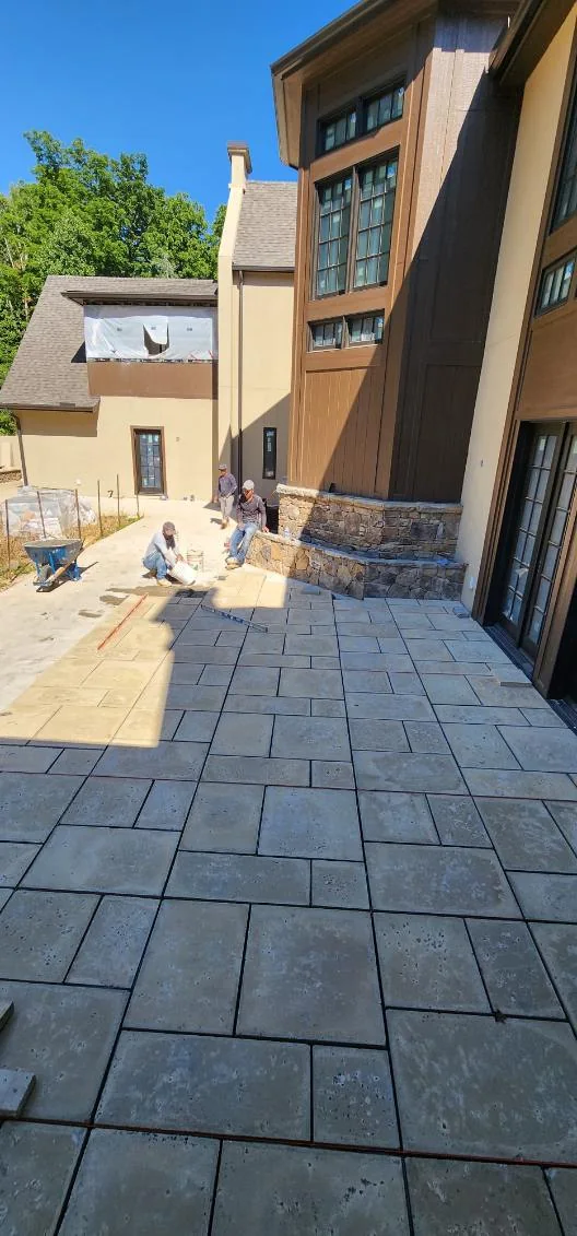 Large-format paver courtyard against a stone-veneer foundation