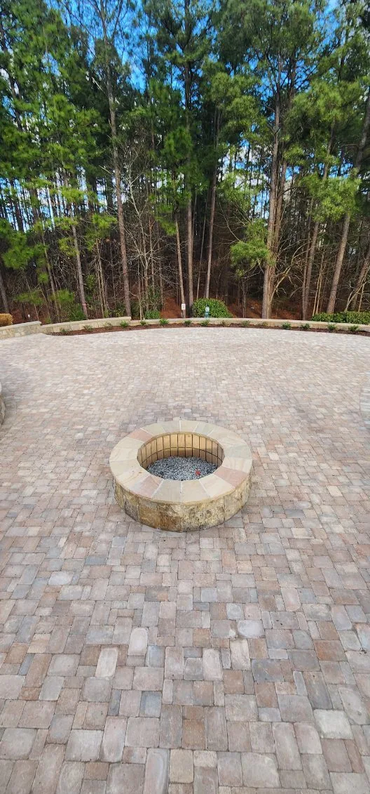Paver patio with a stone fire pit and a low stone border wall