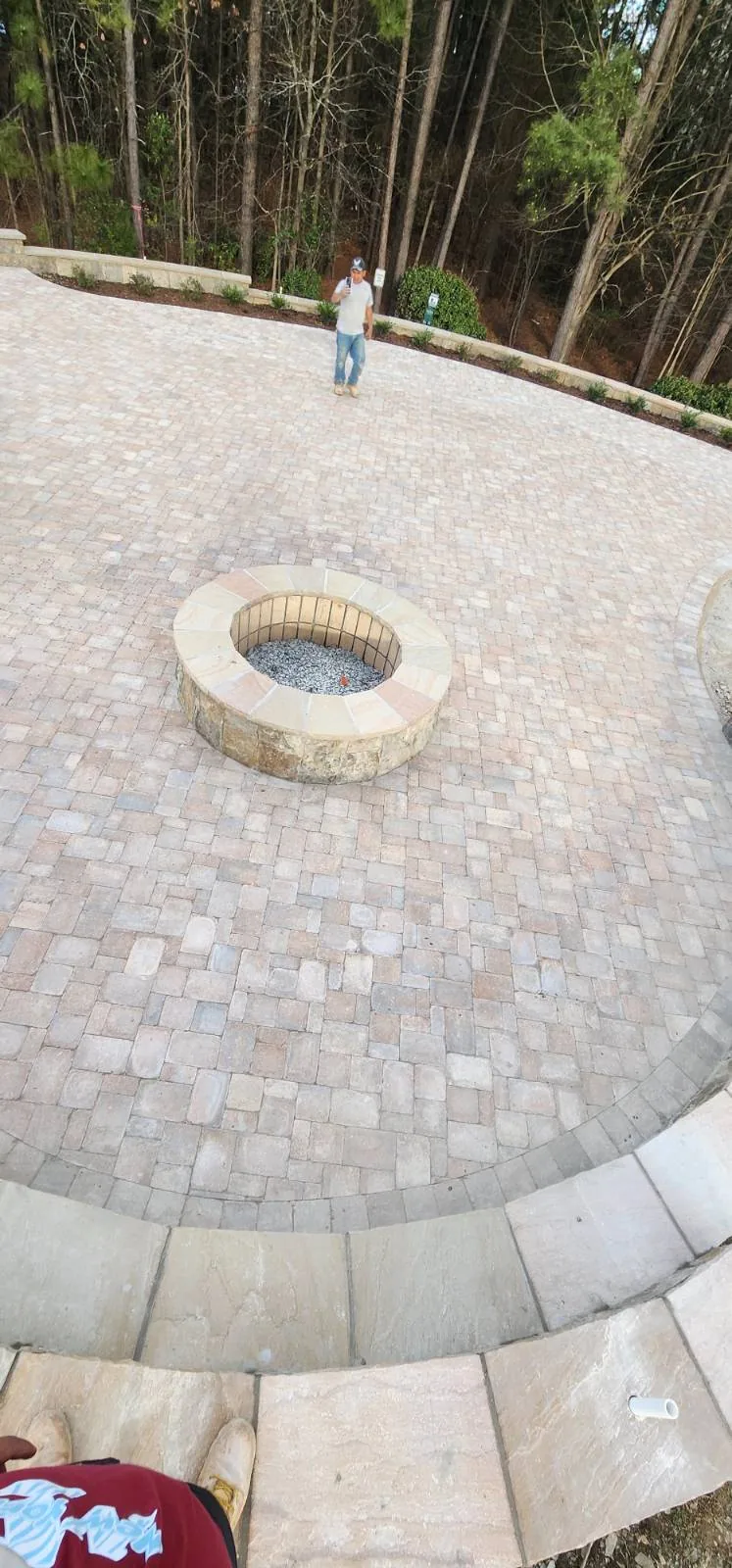 Circular paver patio with a stone fire pit and a curved seat wall