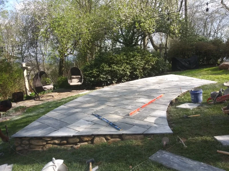 A curved paver patio on a stone-faced raised wall
