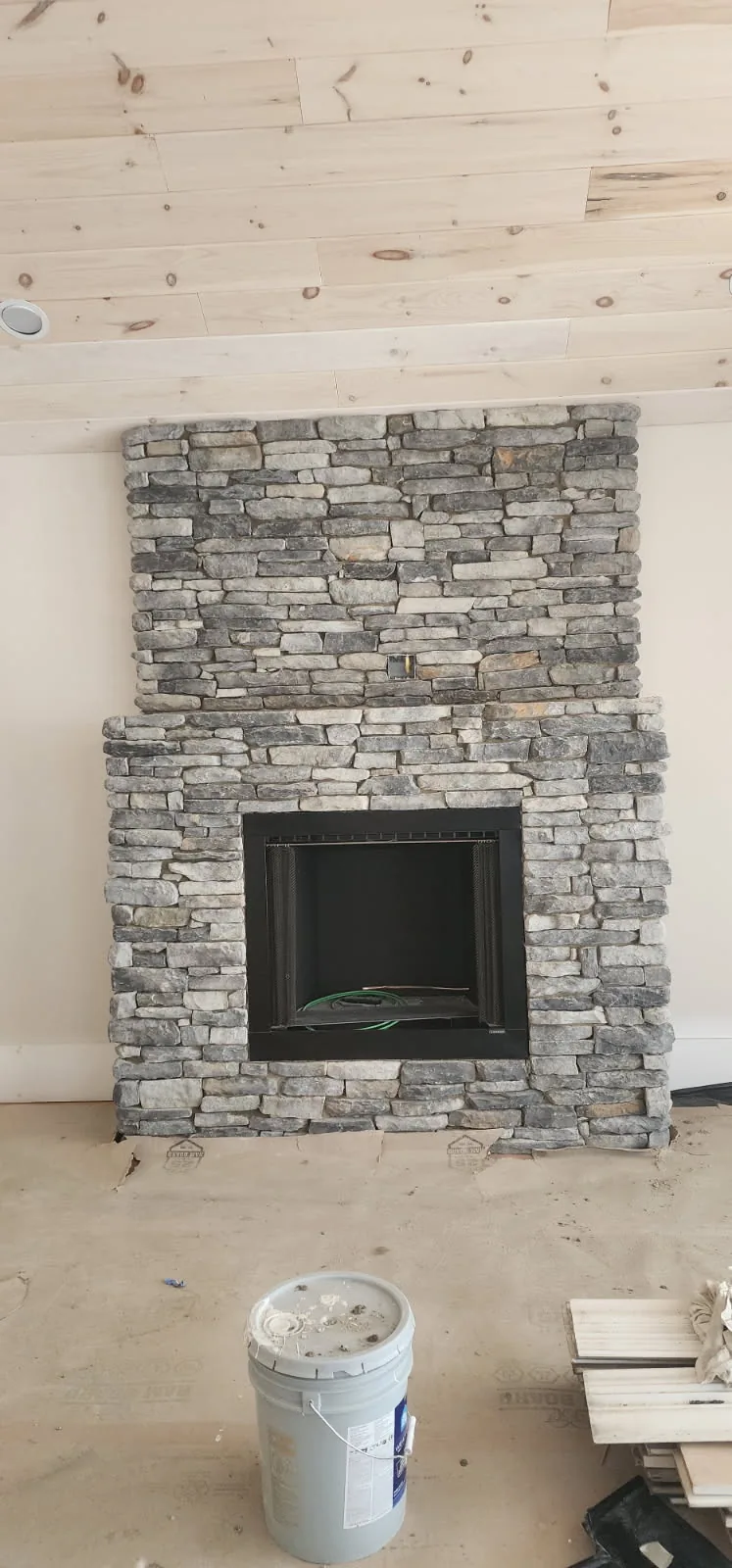 Floor-to-ceiling stacked-stone veneer fireplace